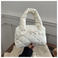 Détail du sac à main matelassé beige avec nœud en métal doré et texture élégante - Blanc