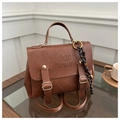 Detail of vintage brown PU leather backpack with embossed text and knot charm on wood table - With Charm / Brown
