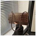 Detailed view of dark brown faux crocodile leather texture and golden metal buckle on bag - Coffee