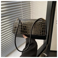 Close-up of black crocodile texture flap with gold trim on a vintage shoulder bag - Black