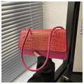 Detail of pink faux crocodile skin texture and gold metallic trim on a crossbody bag - Pink