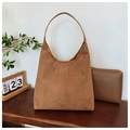 Détail du grand sac hobo en daim caramel et sa pochette zippée sur une table en bois - Kaki