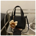 Black pebble leather bucket bag with top handles and decorative plush charm detail - Black With Pendant
