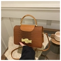 Chic brown stone-textured crossbody bag with unique golden circular handle and wave clasp - Brown