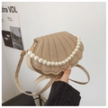 Detalle de bolso de concha tejida caqui con elegante asa de perlas y correa fina - Dorado