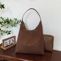 Bolso hobo de ante marrón con neceser a juego en un entorno de estilo de vida cálido - café