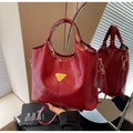 Detailansicht einer roten glänzenden Leder-Beuteltasche mit goldenem Metalldreieck-Beschlag - Burgunderrot