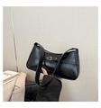 Close-up of black glossy synthetic leather handbag with decorative strap buckle detail - Black