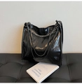 Detail der schwarzen glänzenden PU-Leder Tote Bag mit silberner Kette auf Sofa - Schwarz