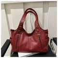 Detail view of large burgundy tote bag featuring front zippers and side pockets on a chair - Red