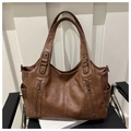 Close-up of dark brown leather tote bag with vertical zippers and pebble grain texture - Brown