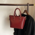 Moderne burgunderrote Beuteltasche mit goldenen Beschlägen und Griffen im minimalistischen Stil - Rot