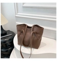 Vista de detalle de bolso tote de cuero marrón con logo grabado sobre podio blanco curvo - café