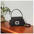 Elegante bolso negro brillante con hebilla de strass sobre una mesa de madera - Negro