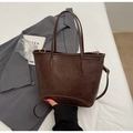 Detail view of dark brown leather bucket bag with top handles and adjustable strap - Coffee