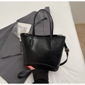 Detail of black textured faux leather tote bag with gold hardware and fashion embossing - Black