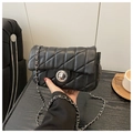 Chic black quilted chain shoulder bag with silver clasp in a stylish hand-held pose - Black