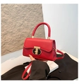 Detalle de bolso bandolera de cuero rojo con un cierre giratorio circular dorado y negro - Rojo