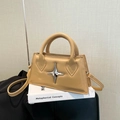 Sac bandoulière beige chic avec étoile métallique posé sur un livre pour un look tendance - Kaki