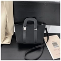 Detail of black crossbody bag with curved top handle on a minimalist elegant background - Black