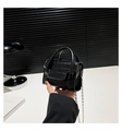 Close-up of black crocodile pattern mini bag with silver chain held in hand - Black
