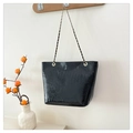 Detail van zwarte tas met krokodillenreliëf en gouden ketting aan een houten wandhaakje - Zwart