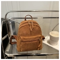 Detail of a brown corduroy backpack displayed on a shelf with art books and coffee - Brown
