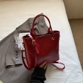 Primer plano detallado de un bolso tipo cubo de cuero rojo vintage con herrajes dorados - Burdeos