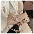 Detailed close-up of beige shoulder bag featuring decorative cross straps and gold buckles - Khaki