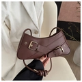 Detailed close-up of dark brown crescent bag with gold buckles and knotted shoulder strap - Brown