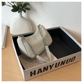 Minimalist beige woven hobo bag with a silver chain strap shown in a modern home setting - Khaki
