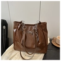 Detail of a brown glossy tote bag featuring a silver metal bow and chunky chain strap - Brown Without Pendant