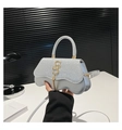 Dettaglio della borsa con paillettes argento, logo SS dorato e nappina su tavolo - Argento