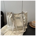 Detail of cream tote bag featuring textured leather, metal bow and chain shoulder strap - White Without Pendant