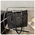 Close-up of black tote bag with twill texture and silver chain leather strap on shelf - Black Without Pendant