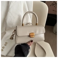 Detalle de un bolso de cuero blanco crema con cierre dorado y acabado de lujo pulido - Caqui