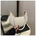 Detail of white half-moon bag featuring red lining, lychee texture, and gold hardware - White