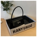 Detail of glossy black underarm bag with a gold metal bow on a minimalist display - Black