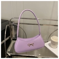 Detail einer hellvioletten Ledertasche mit goldener Schleife auf einem Metallregal - Lila