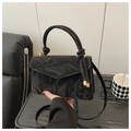 Detail of black textured handbag with knot handle and elegant gold hardware accents - Large / Black