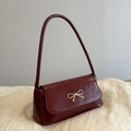 Minimalist burgundy patent leather shoulder bag with a gold bow clasp and sleek strap - Burgundy