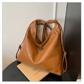 Detalle del bolso de cuero marrón caramelo con logo metálico triangular y textura suave - Marrón