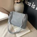 Grande borsa tote grigia intrecciata con catena argento in un ambiente minimalista - Blu