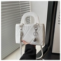 Close-up of white quilted handbag featuring silver ball charm and metallic ring hardware - White