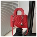 Close-up of red quilted handbag featuring silver ball charm and textured faux leather - Red