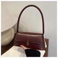 Close-up of burgundy vintage leather bag with an antique bronze clasp on a wooden table - Dark Brown