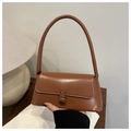 Close-up of caramel brown minimalist baguette shoulder bag with metallic buckle closure - Tan
