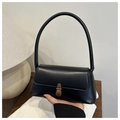 Close-up of black leather handbag with gold metal clasp and sleek cylindrical handle - Black