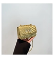 Detailed close-up of golden V-quilted mini chain bag with metallic finish and twist lock - Gold