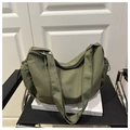 Primer plano de un bolso tote de nailon verde militar con correa ajustable en silla - Verde